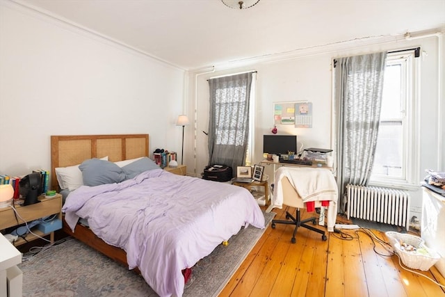 bedroom featuring hardwood / wood-style flooring, crown molding, and radiator