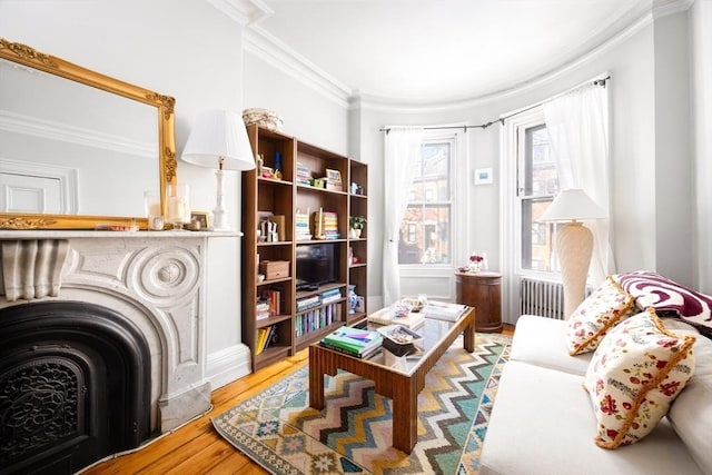 sitting room with radiator heating unit, ornamental molding, and wood-type flooring