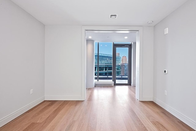 unfurnished room featuring floor to ceiling windows and light hardwood / wood-style flooring