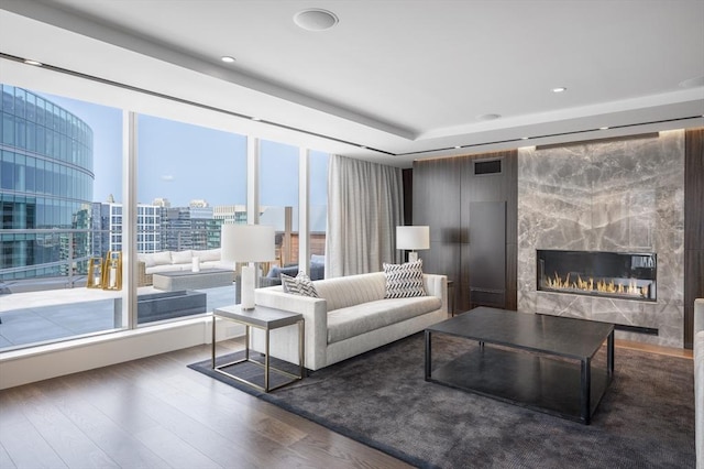 living room with a high end fireplace and dark hardwood / wood-style floors