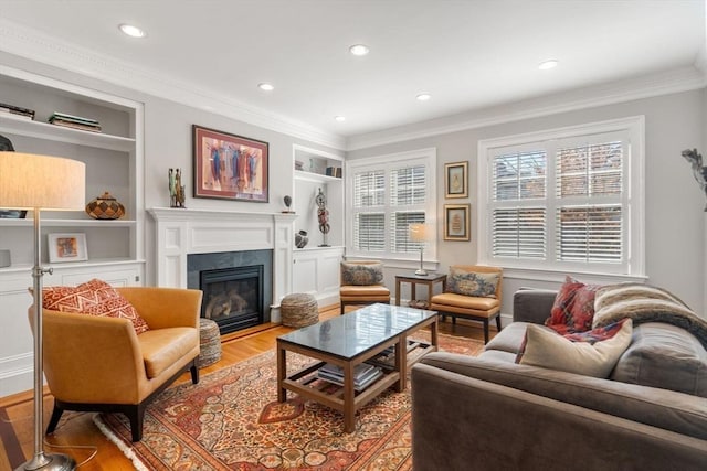 living area featuring a glass covered fireplace, crown molding, and wood finished floors