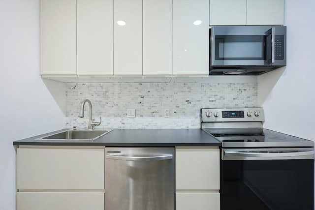 kitchen featuring white cabinets, appliances with stainless steel finishes, tasteful backsplash, and sink