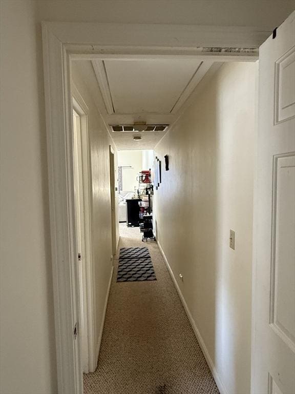 hall featuring attic access, light colored carpet, and baseboards