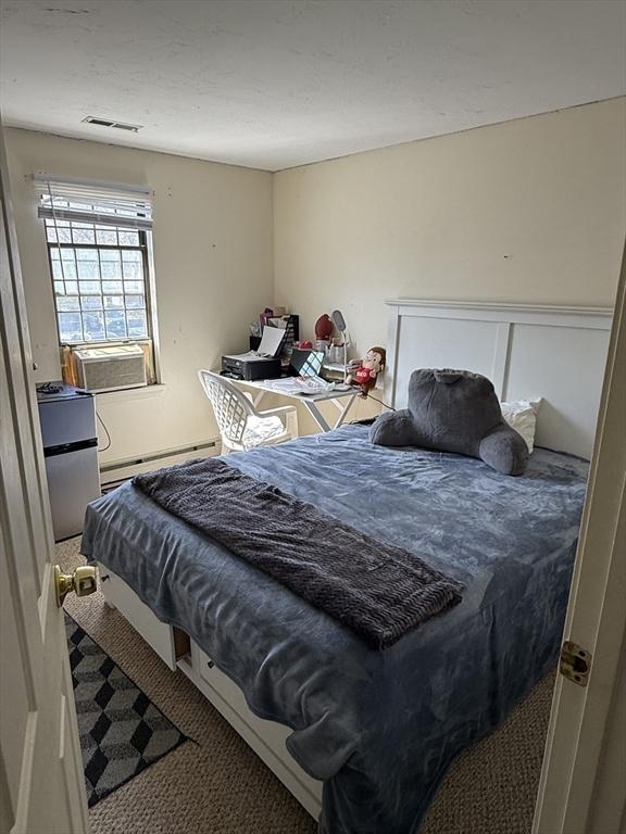 bedroom with a baseboard radiator, carpet floors, and cooling unit