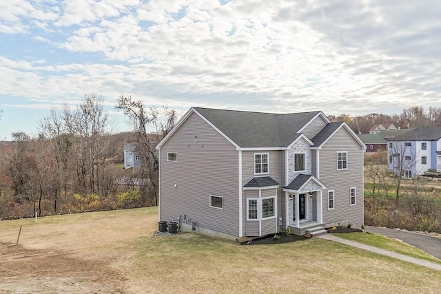 traditional home with a front lawn and a shingled roof