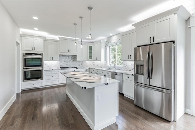 kitchen featuring backsplash, a kitchen island, appliances with stainless steel finishes, and a sink