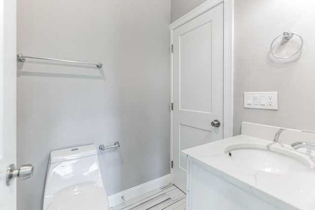 half bathroom with toilet, vanity, and baseboards