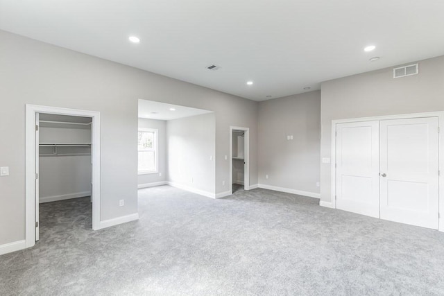 unfurnished bedroom with a spacious closet, visible vents, recessed lighting, and carpet floors