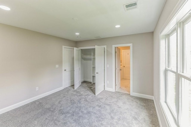 unfurnished bedroom with visible vents, recessed lighting, a closet, baseboards, and light colored carpet