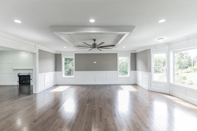 unfurnished living room featuring ornamental molding, wood finished floors, a fireplace, a raised ceiling, and ceiling fan