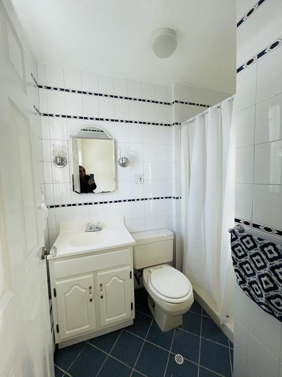 bathroom featuring tile patterned floors, tile walls, vanity, curtained shower, and decorative backsplash