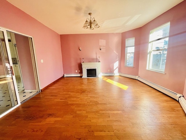 unfurnished living room featuring a chandelier, light wood-type flooring, and baseboard heating