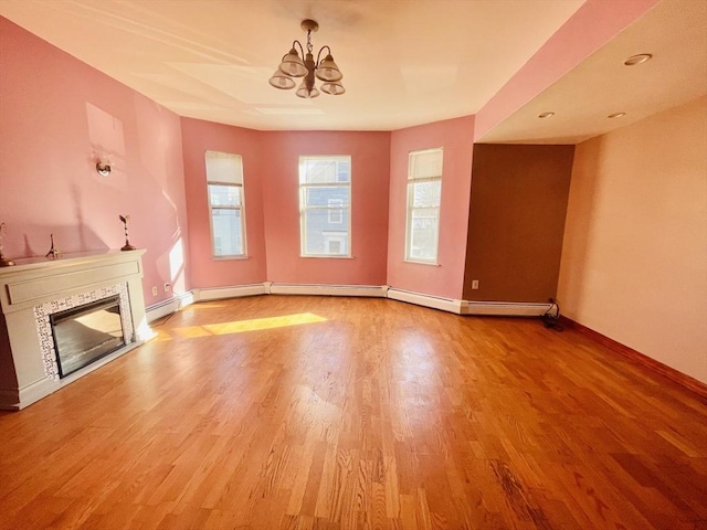 unfurnished living room with a tiled fireplace, light hardwood / wood-style floors, and an inviting chandelier