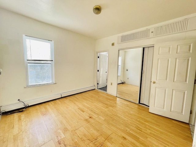 unfurnished bedroom with a baseboard radiator and light wood-type flooring