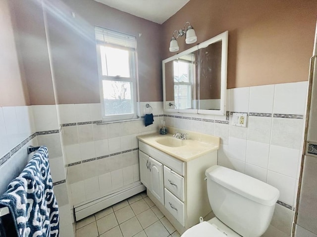 bathroom with a baseboard radiator, tile walls, tile patterned flooring, vanity, and toilet