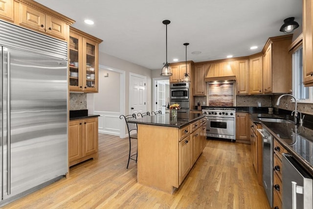 63 High St, Shrewsbury, MA 01545 - kitchen featuring light wood finished floors, high end appliances, custom range hood, a kitchen island, and a breakfast bar area