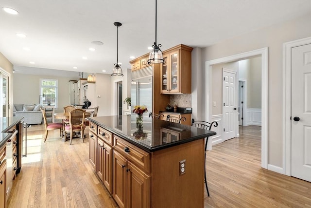 63 High St, Shrewsbury, MA 01545 - kitchen featuring light wood finished floors, glass insert cabinets, brown cabinetry, built in fridge, and a breakfast bar