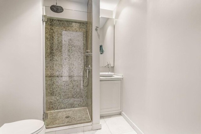 bathroom featuring a shower stall, vanity, tile patterned floors, baseboards, and toilet