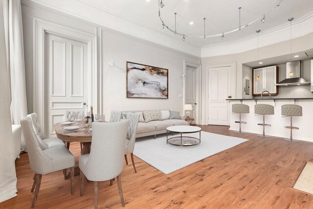 living area with rail lighting, light wood-style flooring, and ornamental molding