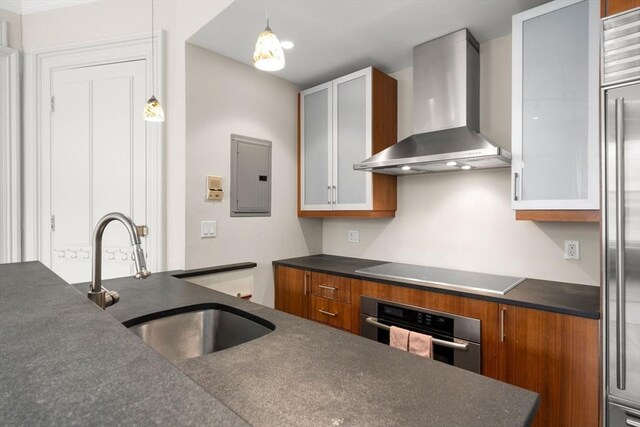 kitchen featuring dark countertops, wall chimney range hood, electric panel, a sink, and appliances with stainless steel finishes
