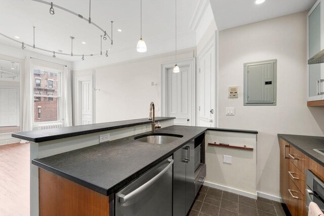 kitchen featuring stainless steel dishwasher, dark countertops, brown cabinets, electric panel, and a sink