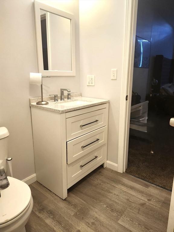 202 Broadway Unit 2-1, Lawrence, MA 01840 - bathroom with wood finished floors, vanity, toilet, and baseboards