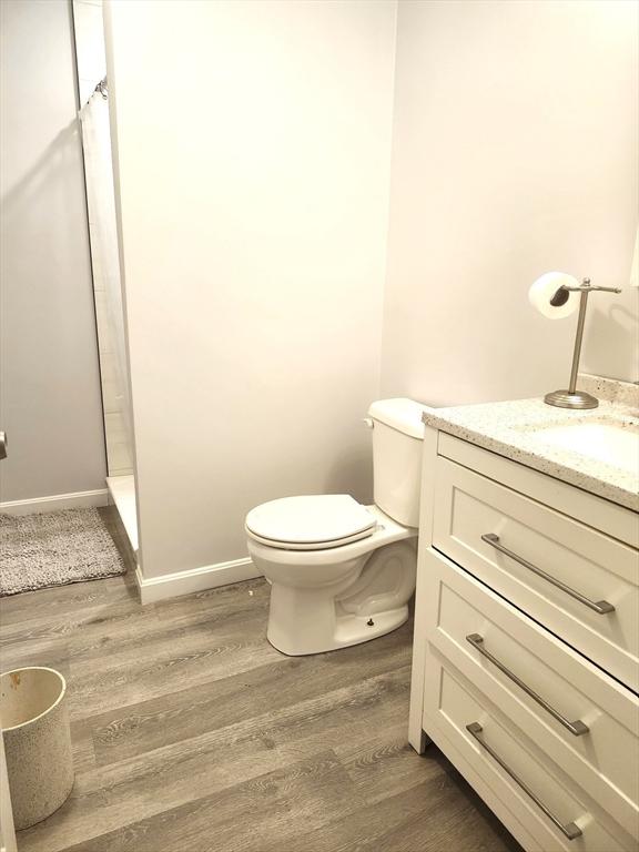 202 Broadway Unit 2-1, Lawrence, MA 01840 - full bath featuring wood finished floors, a stall shower, vanity, toilet, and baseboards