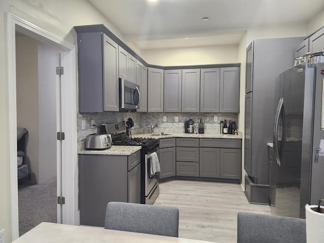 202 Broadway Unit 2-1, Lawrence, MA 01840 - kitchen with appliances with stainless steel finishes, gray cabinetry, a sink, backsplash, and light wood finished floors