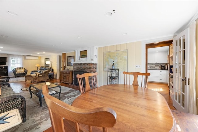 34 Kenwood Rd, Bourne, MA 02559 - dining area with a brick fireplace, light wood-type flooring, an AC wall unit, and recessed lighting