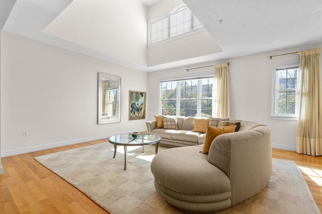 living room featuring light wood-type flooring, plenty of natural light, and a towering ceiling