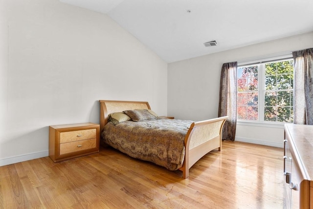 bedroom with light wood-type flooring and vaulted ceiling