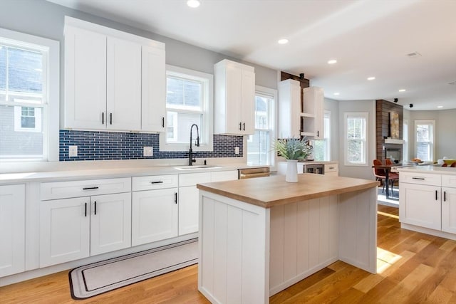61 Paul Revere Rd Unit 2, Arlington, MA 02476 - kitchen featuring light wood finished floors, backsplash, white cabinets, and a sink