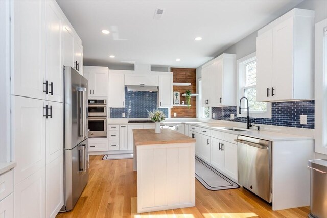61 Paul Revere Rd Unit 2, Arlington, MA 02476 - kitchen with a sink, stainless steel appliances, white cabinets, under cabinet range hood, and decorative backsplash