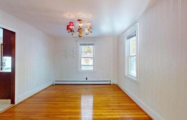 unfurnished room featuring an inviting chandelier, hardwood / wood-style floors, a healthy amount of sunlight, and baseboard heating