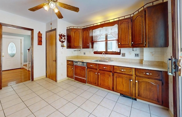 kitchen with sink, tasteful backsplash, light tile patterned floors, ceiling fan, and paneled dishwasher