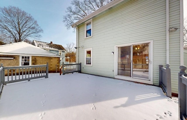 snow covered back of property with a deck