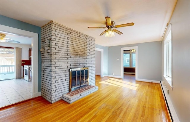 unfurnished living room with a brick fireplace, a wealth of natural light, and a baseboard radiator