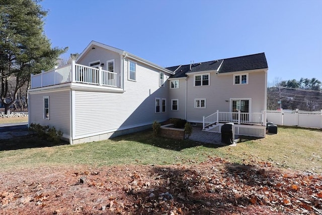 rear view of house with a lawn and a balcony