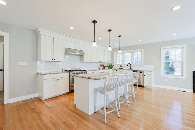 kitchen with white cabinetry, light stone counters, stainless steel appliances, and a kitchen island