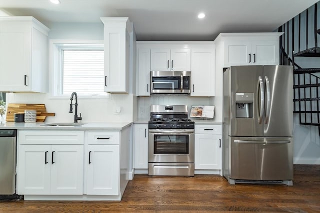 221 Paris St Unit 1, Boston, MA 02128 - kitchen with appliances with stainless steel finishes, white cabinets, decorative backsplash, recessed lighting, and dark wood-type flooring