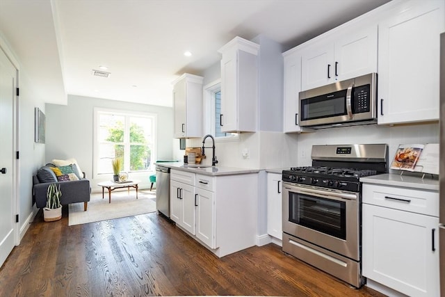 221 Paris St Unit 1, Boston, MA 02128 - kitchen with appliances with stainless steel finishes, dark wood finished floors, white cabinetry, recessed lighting, and light countertops