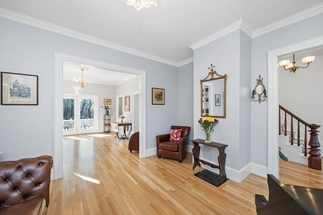 sitting room with baseboards, an inviting chandelier, light wood-style flooring, ornamental molding, and stairs