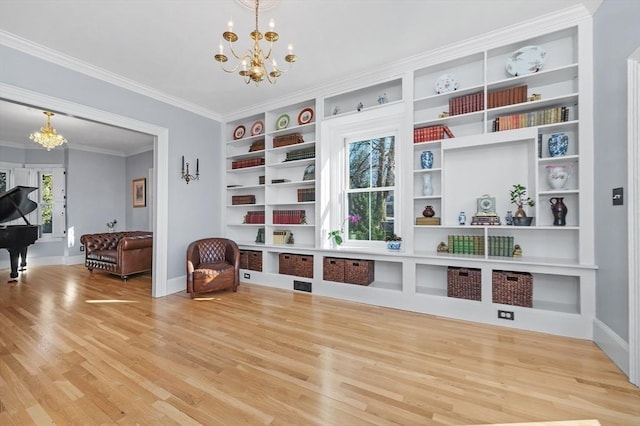 living area featuring a chandelier, crown molding, baseboards, and wood finished floors