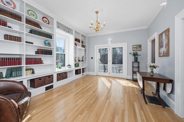 sitting room with built in shelves, baseboards, an inviting chandelier, light wood-style flooring, and crown molding