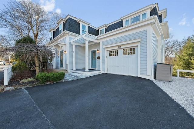 view of front of house featuring mansard roof, roof with shingles, an attached garage, and aphalt driveway