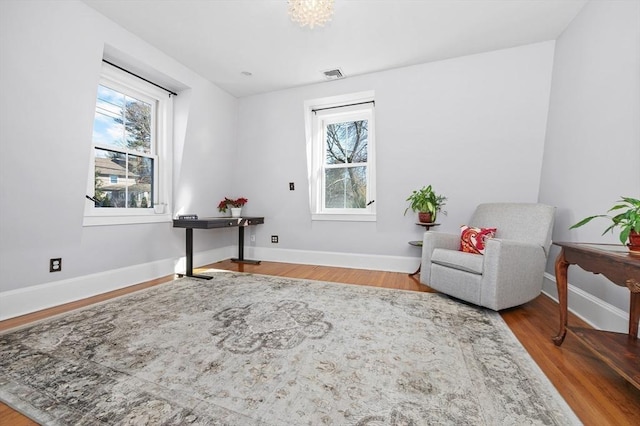 living area featuring wood finished floors, visible vents, a wealth of natural light, and baseboards