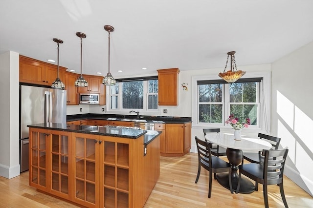 kitchen with pendant lighting, brown cabinets, light wood-style floors, and appliances with stainless steel finishes