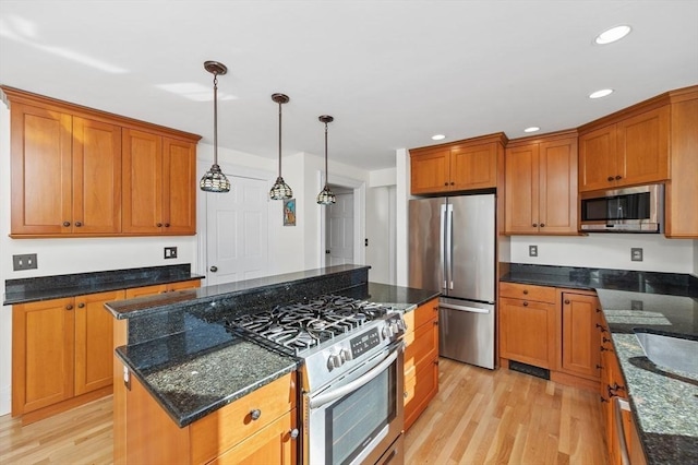 kitchen featuring brown cabinetry, appliances with stainless steel finishes, a kitchen island, and light wood-type flooring