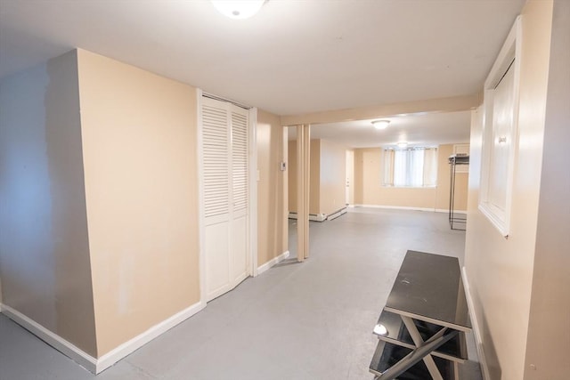 corridor with a baseboard radiator, finished concrete floors, and baseboards