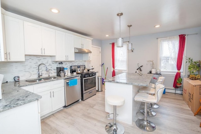 kitchen featuring white cabinets, under cabinet range hood, stainless steel appliances, and a sink